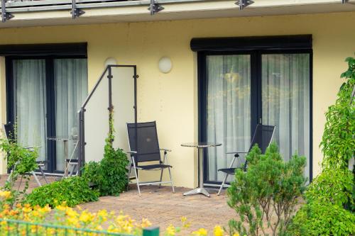 a patio with two chairs and a table and windows at aktiv Sporthotel Sächsische Schweiz in Pirna