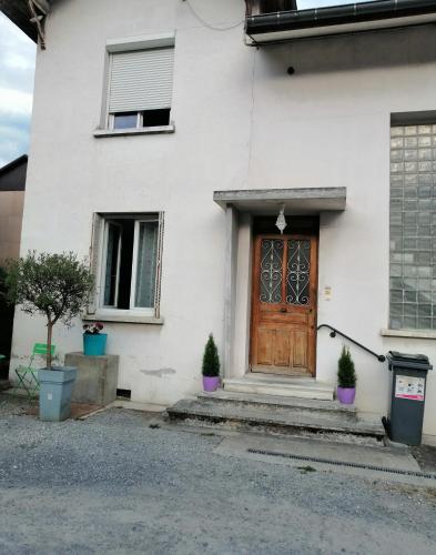 a white house with a wooden door and two potted plants at Résidence Mirage avec vidéo surveillance in Albertville