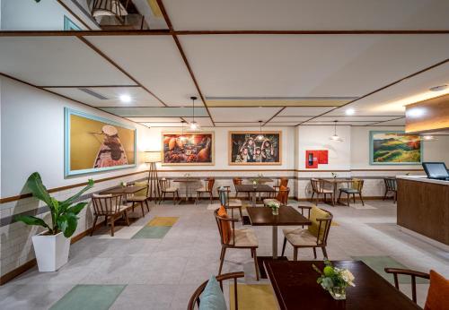 a restaurant with tables and chairs and paintings on the walls at Icon Saigon - LifeStyle Design Hotel in Ho Chi Minh City