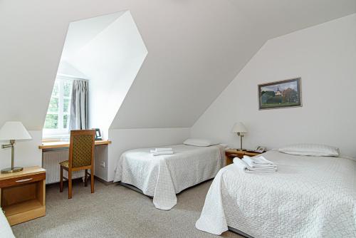 a bedroom with two beds and a desk and a window at Domus Maria in Vilnius