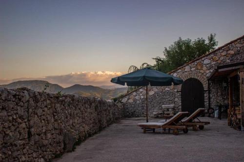 a couple of chairs and an umbrella next to a stone wall at La Caprareccia in Fiumata