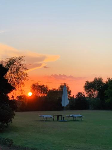 two benches and an umbrella with the sunset in the background at B&B Beauty House in Cesena