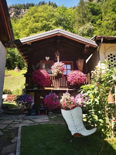 a white chair in front of a house with flowers at Maison Le Cler in Valtournenche