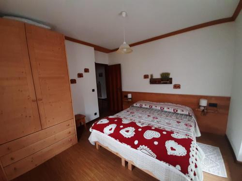 Schlafzimmer mit einem Bett mit einer roten und weißen Tagesdecke in der Unterkunft Appartamento al Pelmo in Villanova