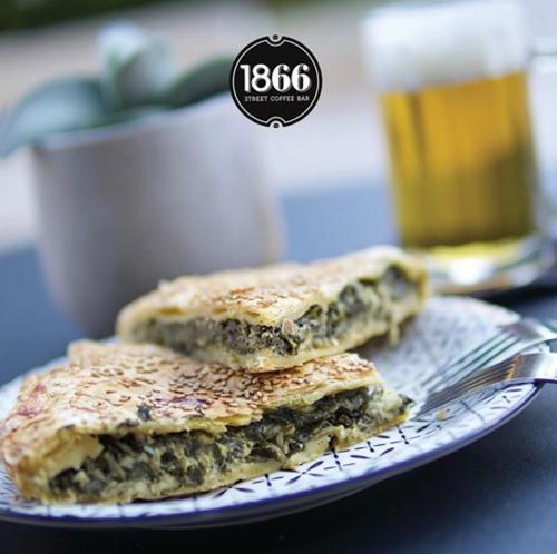 two sandwiches on a plate with a fork and a drink at Olympic Hotel in Heraklio Town