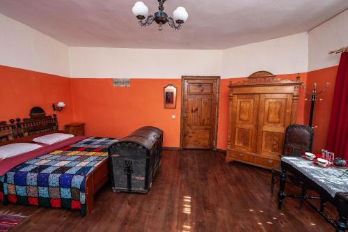 a bedroom with orange walls and a bed and a table at Baltā māja in Pilsrundāle