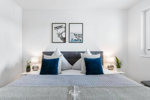 1 dormitorio blanco con 1 cama grande con almohadas azules en MeerLeben en Olpenitz