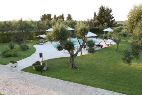 a garden with a pool and a tree in the grass at Masseria Un Posto al Sole in Otranto