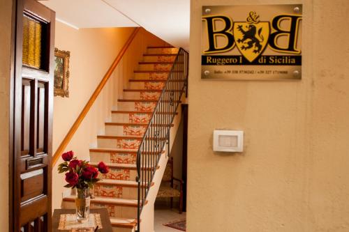a spiral staircase with a vase of flowers on a table at B&B Ruggero I di Sicilia in Piazza Armerina