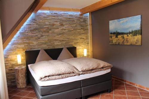 Bett in einem Zimmer mit Ziegelwand in der Unterkunft Appartements im "Landhaus am Frohnauer Hammer" in Annaberg-Buchholz