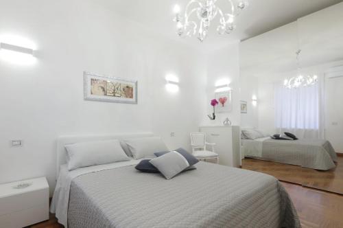 a white bedroom with two beds and a chandelier at La Roma di Cecilia in Rome