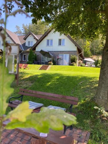 a park bench in a yard with a house at Lesny Apartament in Ostrzyce