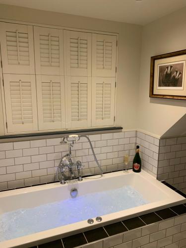 une grande baignoire avec une bouteille de vin. dans l'établissement Jenson Cottage, à Skirpenbeck