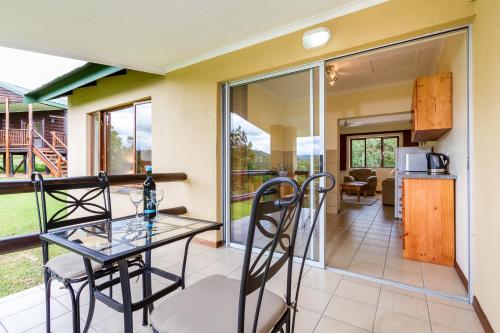 a dining room and kitchen with a glass table and chairs at Cuckoo Ridge Country Retreat in Hazyview