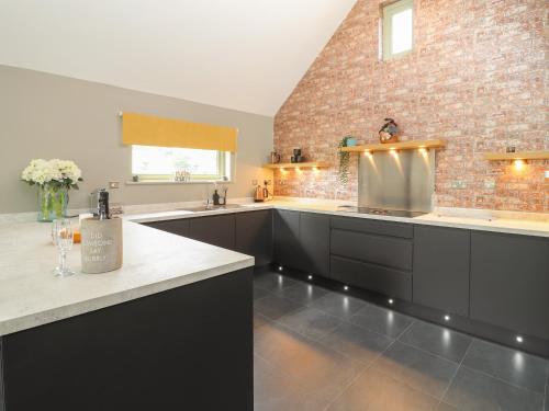 uma grande cozinha com armários pretos e uma parede de tijolos em The Parlour em Telford
