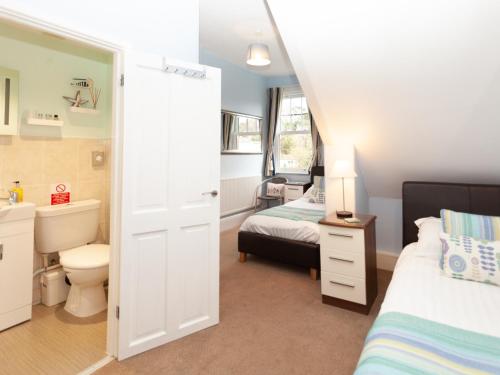 1 dormitorio con 2 camas, lavabo y aseo en The Ravenswood B&B, en Torquay