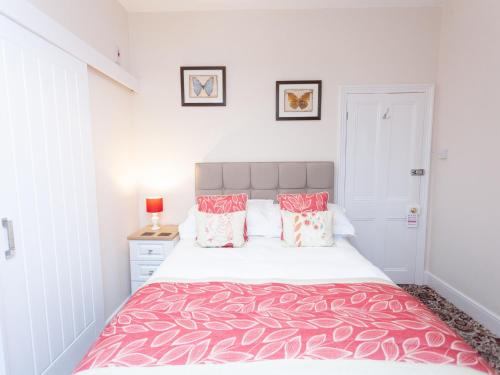 a bedroom with a large bed with red and white sheets at The Ravenswood B&B in Torquay