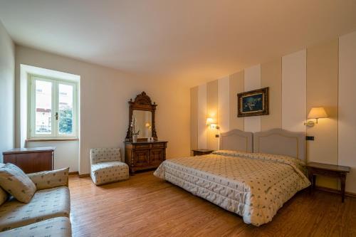 1 dormitorio con cama, sofá y espejo en Locanda La Posta, en Cavour