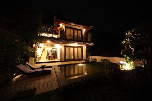 a house at night with a pool in front of it at Baruna Sari Villa in Ubud