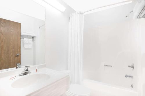 a white bathroom with a sink and a mirror at Microtel Inn & Suites by Wyndham Fond Du Lac in Fond du Lac