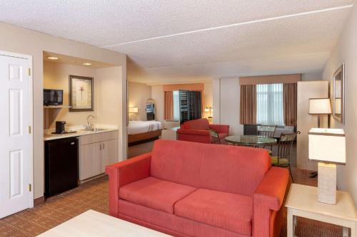 a living room with a red couch in a hotel room at La Quinta by Wyndham Garden City in Garden City