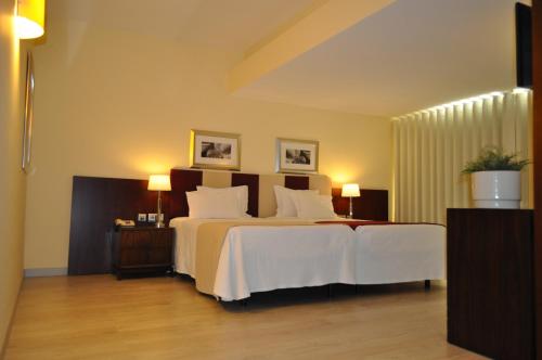 a bedroom with a large bed with white sheets at Santana Hotel & SPA in Vila do Conde