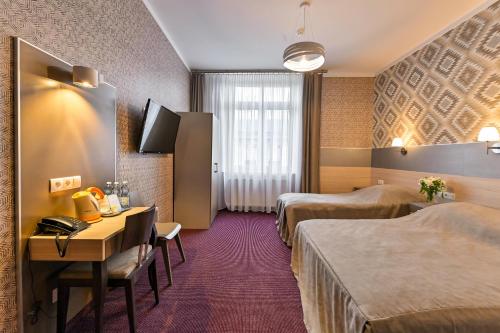 a hotel room with two beds and a desk at Hotel Kazimierz in Krakow