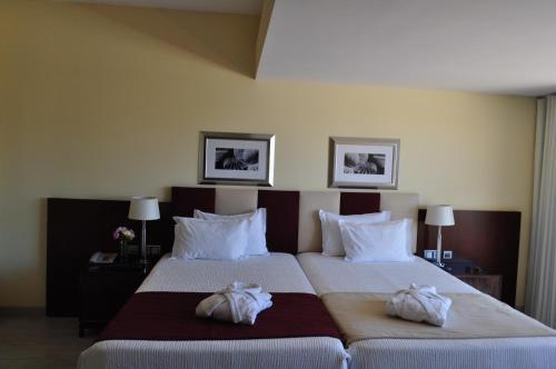 two beds in a hotel room with towels on them at Santana Hotel & SPA in Vila do Conde