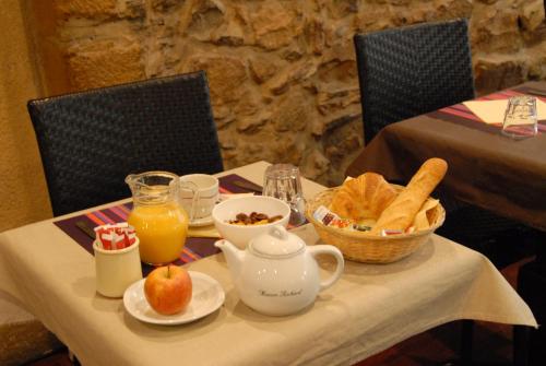 Una mesa con una tetera y un tazón de pan y jugo de naranja. en Hotel de Bretagne, en Lyon