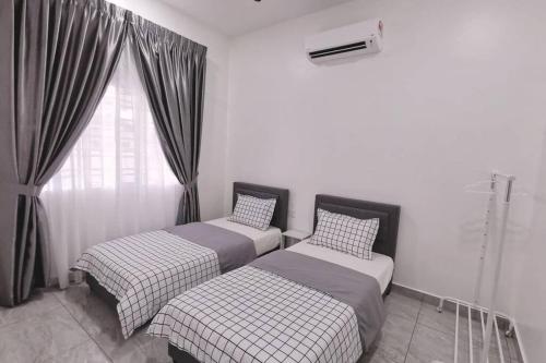 two twin beds in a room with a window at Stay Inn Sikamat (Seremban Homestay) in Seremban