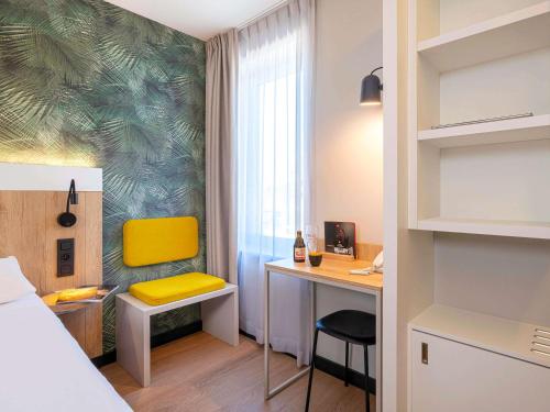 Habitación con cama y escritorio con silla amarilla. en ibis Brussels Waterloo, en Waterloo