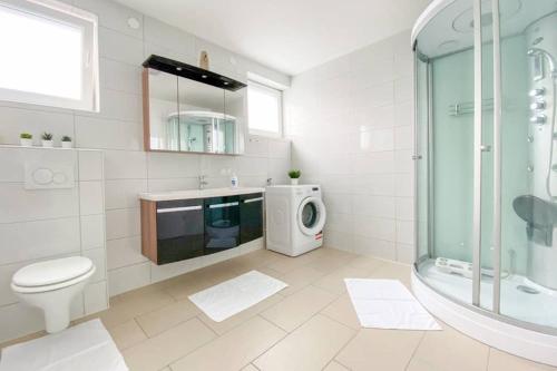 a bathroom with a shower toilet and a washing machine at DAREBELL Apartment Gratkorn Top 3 in Gratkorn