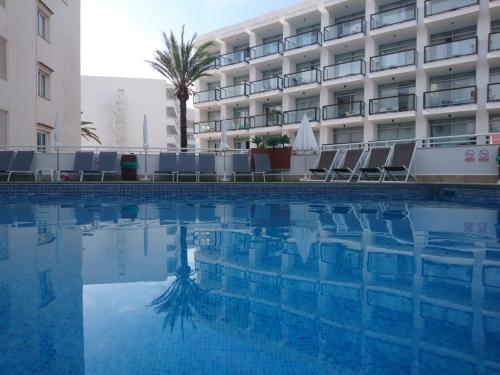 a swimming pool in front of a hotel at Apartamentos Es Cañe in Es Cana