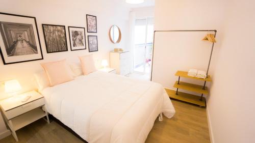 Dormitorio blanco con cama blanca y cuadros en la pared en RentalSevilla Elegante y luminoso apartamento en Triana, en Sevilla