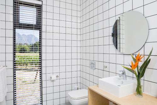 a white tiled bathroom with a sink and a mirror at Gite in Franschhoek