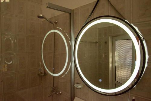 a bathroom with a round mirror and a shower at Guesthouse Belle View in Berat