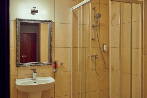 a bathroom with a sink and a shower with a mirror at Zajazd Srebrna Gora in Kraków
