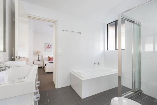 a white bathroom with a tub and a sink at Spacious Two-Bedroom Apartment near Hospital DUPLICATE in Sydney