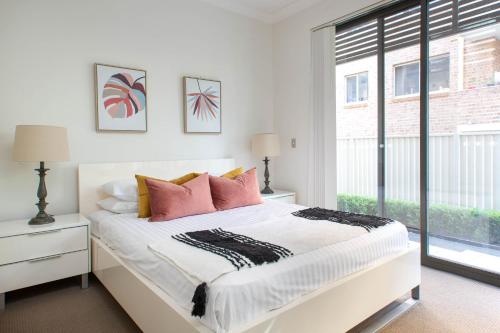 a white bedroom with a large bed with pink pillows at Spacious Two-Bedroom Apartment near Hospital DUPLICATE in Sydney