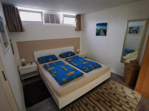 een slaapkamer met een bed met blauwe lakens en een spiegel bij Ferienhaus Lavendel für 1-4 Personen in Überlingen
