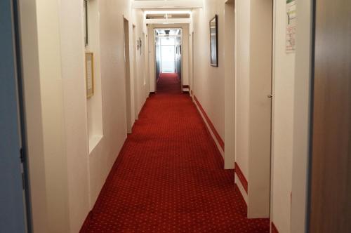 a long corridor with a red carpet in a hallway at Hotel Neuses in Cuxhaven