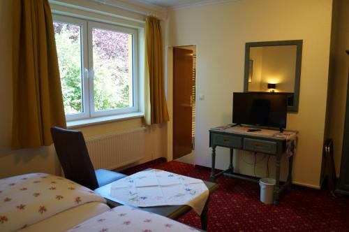 Habitación con cama, espejo y TV. en Hotel Neuses, en Cuxhaven