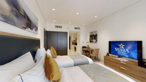 a hotel room with two beds and a flat screen tv at SUHA Mina Rashid Hotel Apartments in Dubai