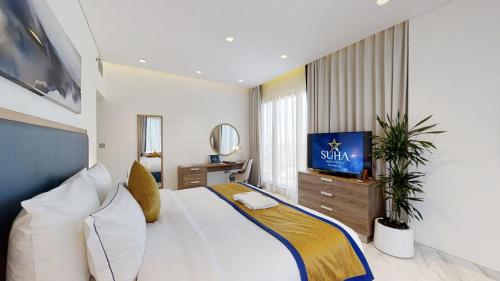 a bedroom with a large white bed and a television at SUHA Mina Rashid Hotel Apartments in Dubai
