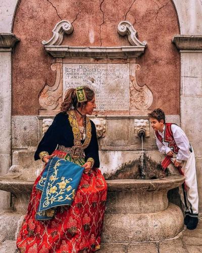 a boy and a woman sitting next to a fountain at GUEST HOUSE PIANA DEGLI ALBANESI in Piana degli Albanesi