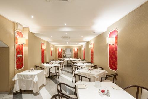 un restaurante con mesas blancas y cuadros rojos en las paredes en Hotel Puccini, en Montecatini Terme