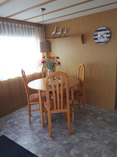 a dining room table and chairs with a vase of flowers on it at AMELAND-Nes-Duinoord: Stacaravan (chalet) + fietsen direct aan zee! in Nes