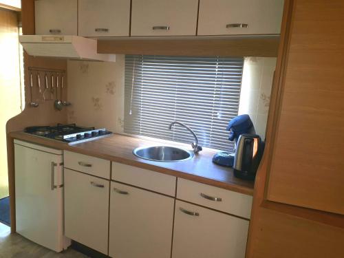 a small kitchen with a sink and a window at AMELAND-Nes-Duinoord: Stacaravan (chalet) + fietsen direct aan zee! in Nes