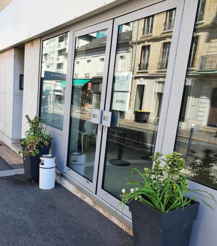 a store front with windows and plants in pots at BRIT HOTEL CONFORT NEVERS Centre Gare in Nevers