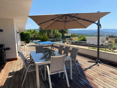 un tavolo con sedie e un ombrellone su una terrazza di Résidence Les Jardins du Fort a Porticcio